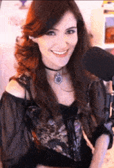 a woman wearing a choker and a necklace smiles in front of a microphone