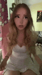 a girl in a white dress sits on a chair in front of a hello kitty curtain