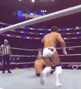 two men are wrestling in a ring with a referee behind them .