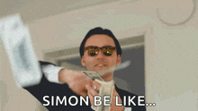 a man in a suit and sunglasses is holding a bunch of money and saying simon be like .