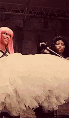 a woman with pink hair is standing next to a woman in a white dress