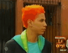 a man with bright orange hair is standing in front of a sign that says ' la oreja '