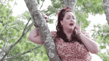 a woman is sitting on a tree branch with her hands on her face .