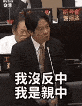 a man in a suit and tie is speaking into a microphone in a foreign language