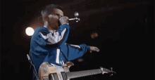 a man is singing into a microphone while holding a guitar .