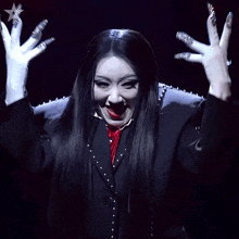 a woman in a black suit and white gloves has a red bow tie