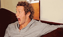 a man with a surprised look on his face is sitting on a couch