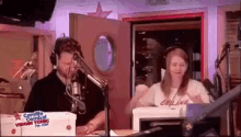 a man and a woman are sitting in front of a microphone in a radio station .
