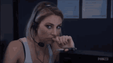 a woman wearing headphones and a microphone is looking at a computer screen .