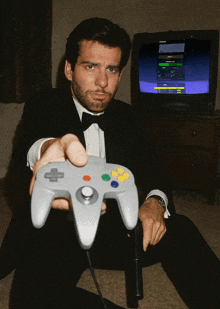 a man in a tuxedo is playing a video game with a controller