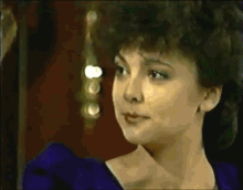 a close up of a woman 's face with a purple dress on .