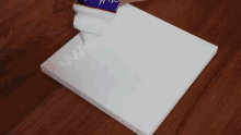 a person is using a spatula to spread purple paint on a canvas