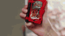 a close up of a person holding a red toy in their hand .