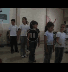 a group of children are standing in a room with a pause button on the screen