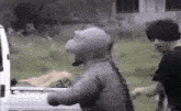 a man in a dinosaur costume is standing in front of a white truck .