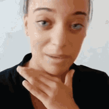 a woman is covering her mouth with her hand and looking at the camera .