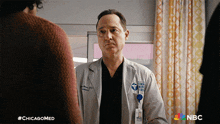 a man in a lab coat is talking to another man with #chicagomed written on the bottom right