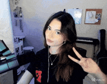 a girl giving a peace sign in front of a piano