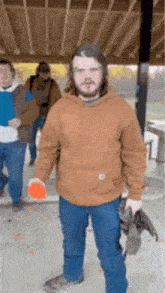 a man in a brown hoodie is standing in front of a group of men .