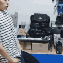 a man in a striped shirt is standing in a room .