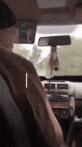 a man driving a car with a rear view mirror hanging from the roof