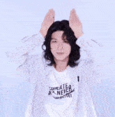 a young man with long hair is wearing a striped shirt and making a heart shape with his hands .