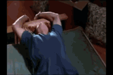 a woman in a blue shirt and shorts is laying on a bed .