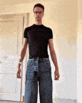 a man wearing glasses and a black shirt is standing in front of a door with tiktok written on the bottom