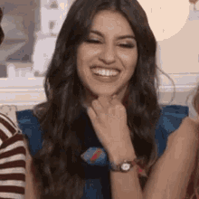 a woman with long hair is smiling with her hand on her chin .