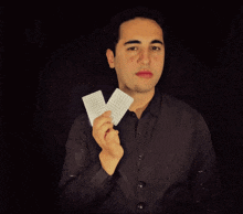 a man in a black shirt is holding two white cards
