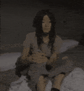a woman sits on a bed with her knees crossed and her eyes closed