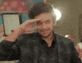 a man in a suit and vest is making a funny face with his hand .