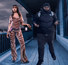 a man and a woman are walking on a balcony and the woman is wearing a zebra print outfit