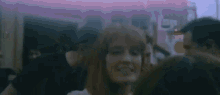 a woman with red hair is smiling in front of a group of people