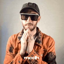 a man wearing sunglasses and a hat has the word mcdh on his shirt