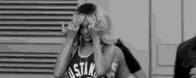 a black and white photo of a woman wearing a basketball jersey .