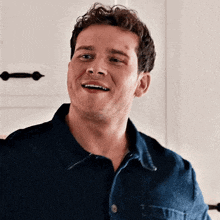 a close up of a man wearing a blue shirt and smiling .