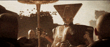 a group of people are gathered around a statue with a triangle on its head