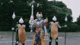 a man in a costume with a sword and shields stands next to two other men