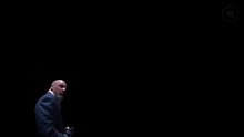 a man in a suit stands in front of a black background with the words ferme ta gueule