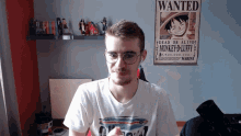 a man sitting in front of a wanted poster of monkey d luffy
