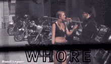 a woman smoking a cigarette in front of a row of motorcycles with the word whore on the bottom right