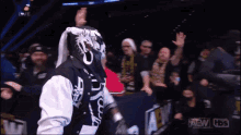 a man wearing a black and white jacket with the word aew on it stands in front of a crowd