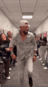 a man in a white hat is dancing in a hallway with a crowd of people .