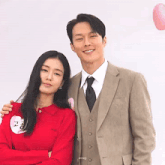 a man in a suit and tie is standing next to a woman in a red shirt