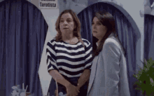 two women standing next to each other in front of a sign that says tarotista