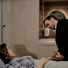 a man in a suit is holding the hand of a woman in a hospital bed