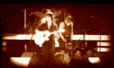 a man playing a guitar on a stage with a drummer behind him
