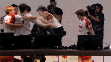 a group of people are hugging each other and one has the number 66 on his shirt