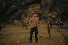 a man is standing in a field surrounded by trees
